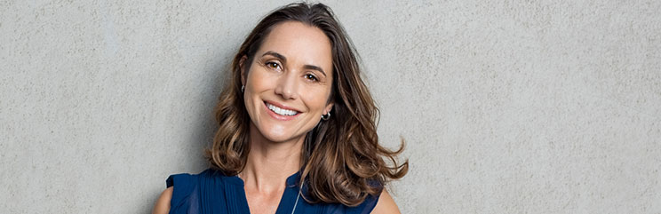 a woman smiles in front of a gray wall